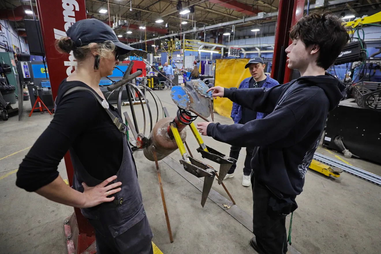 Voc-tech student Landyn Cananzey speaks with DATMA's Lindsay Mis and Matt Moyer Bell about the praying mantis he created in the Greater New Bedford Regional Vocational Technical High School welding shop. The sculpture will be part of an art installation in front of the Buttonwood Park Zoo by DATMA. Photo PETER PEREIRA/The Standard-Times